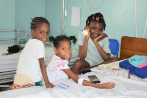 Des enfants assis sur le lit de l'hôpital pédiatrique Saint-Damien en Haiti.