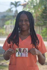 Une fille de notre foyer en haiti tient une photo de sa marraine.